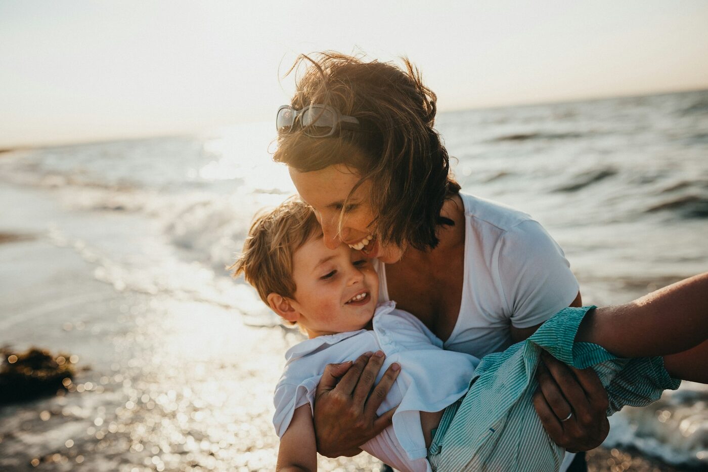A mother holding her young son by the water at golden hour, a family beginning their new life in Canada